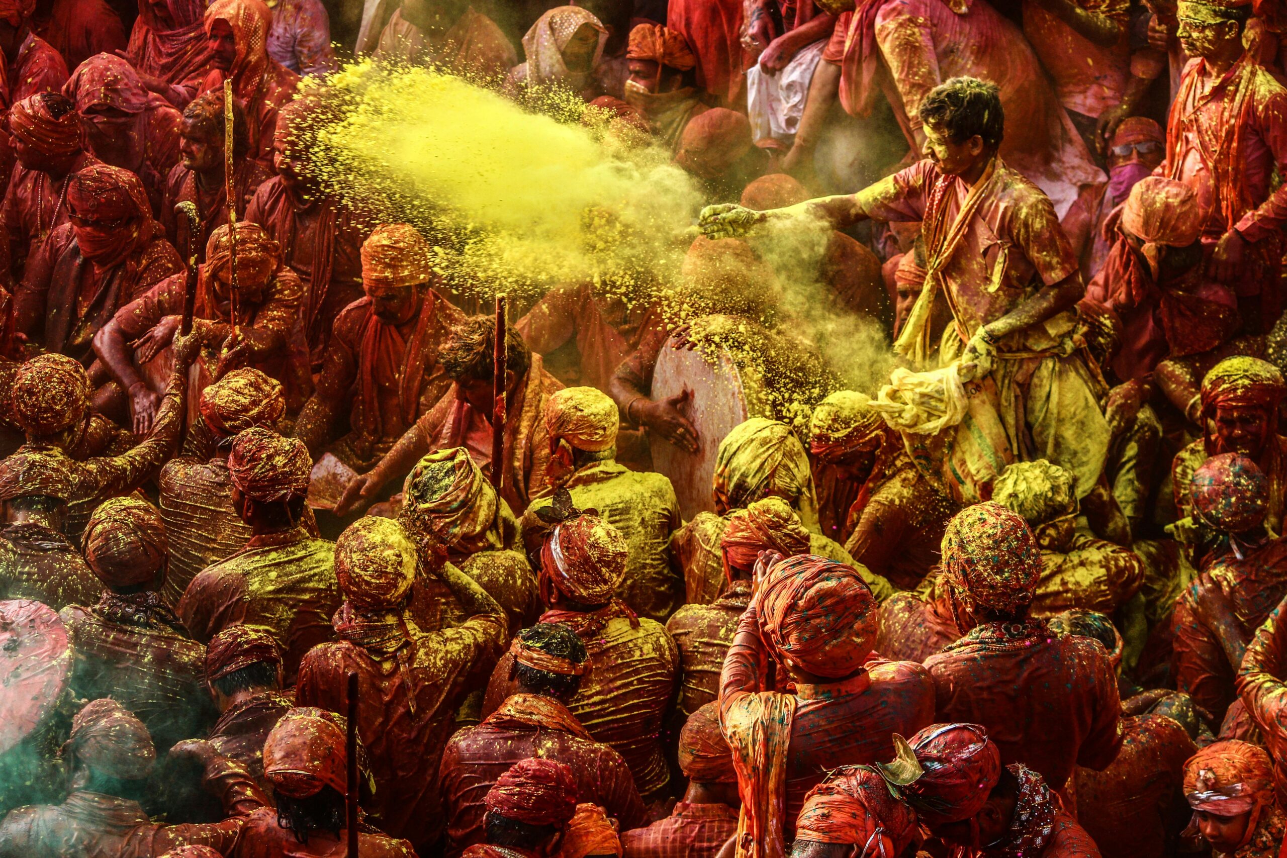 Vibrant crowd celebrating Holi 2026 in India, throwing colorful gulal powder in the air during the traditional festival of colors.